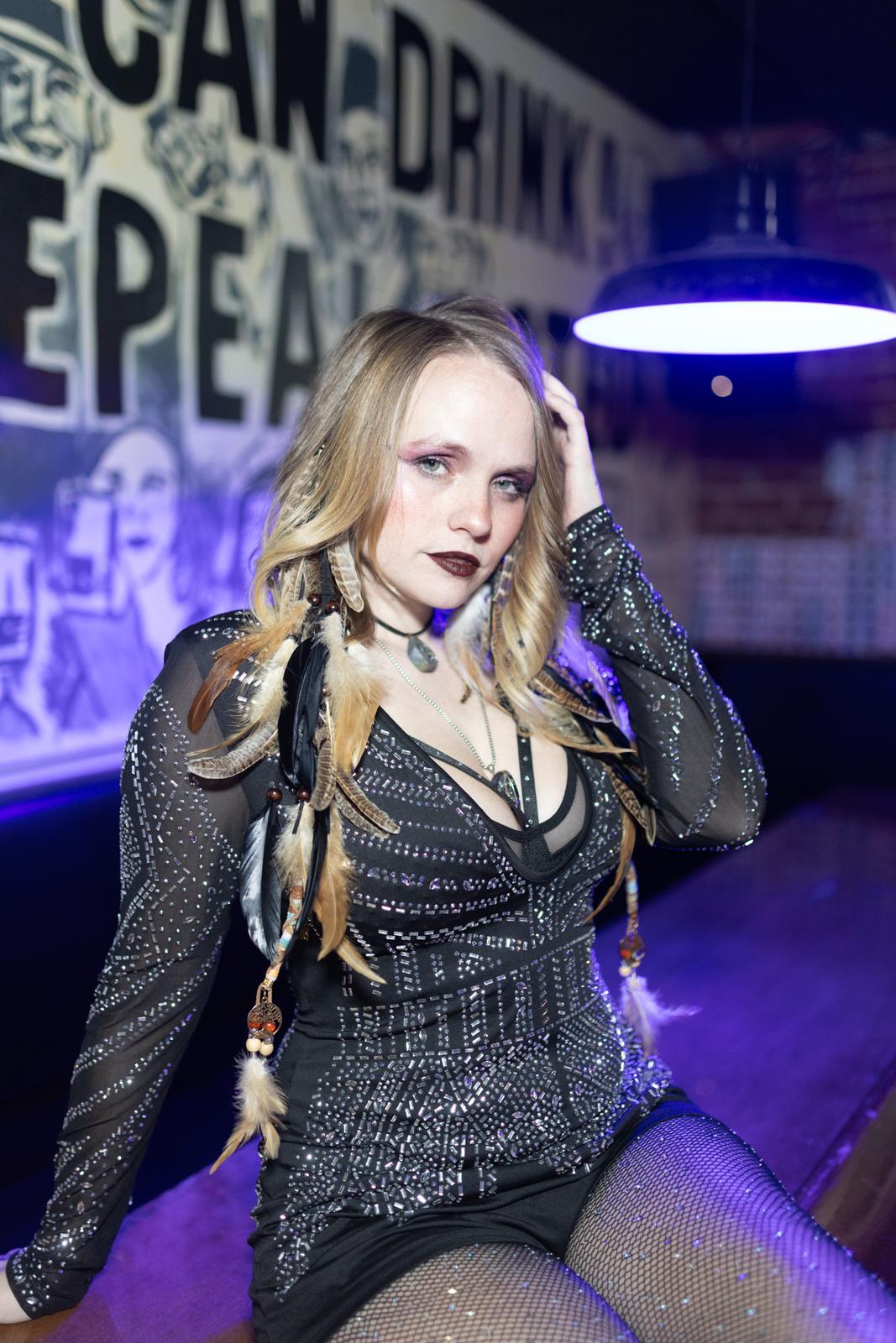 Ariel Jade in a beaded black dress under purple bar light