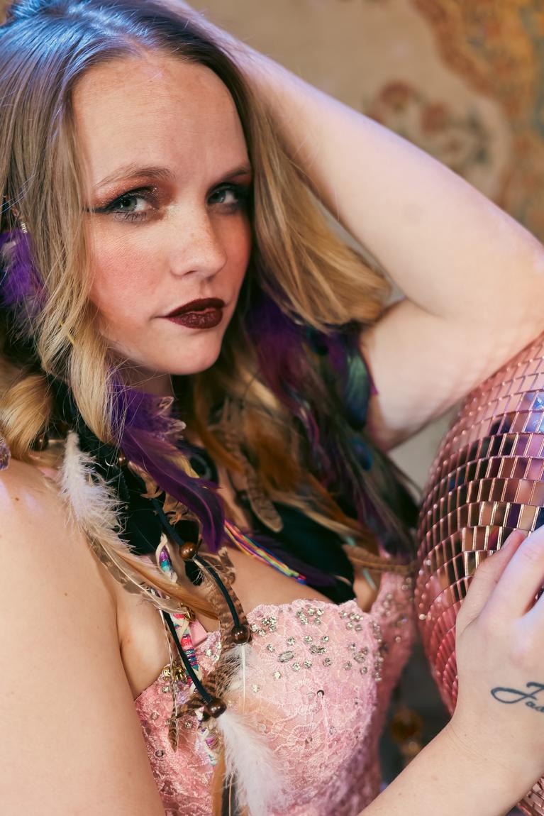 Close portrait of Ariel Jade beside a rose-gold disco ball