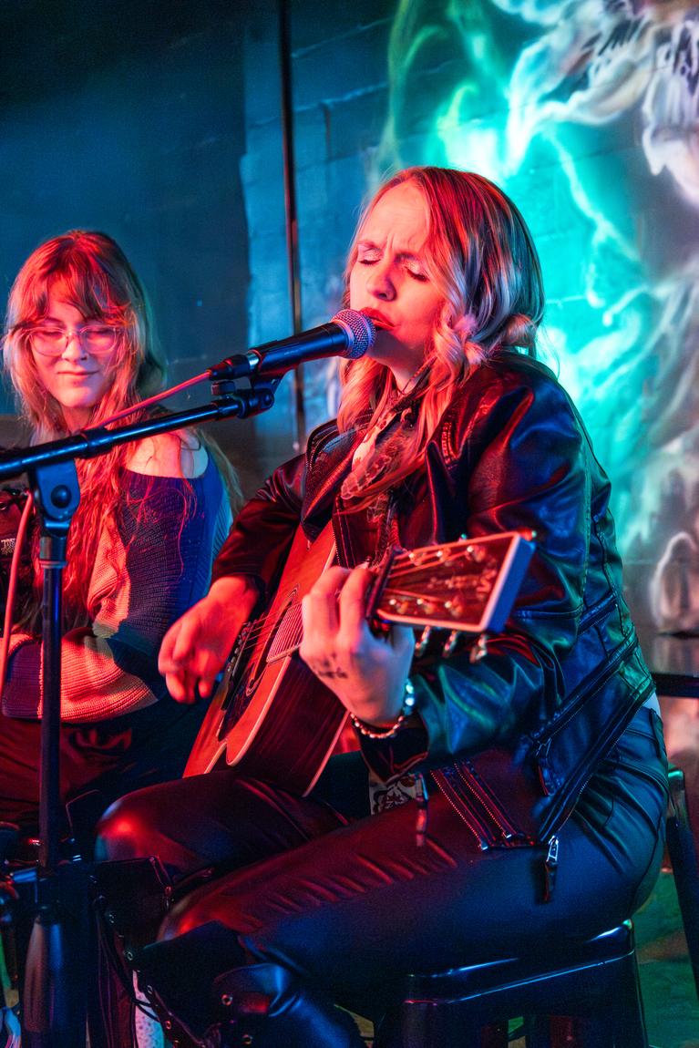 Ariel Jade singing in a leather jacket under neon