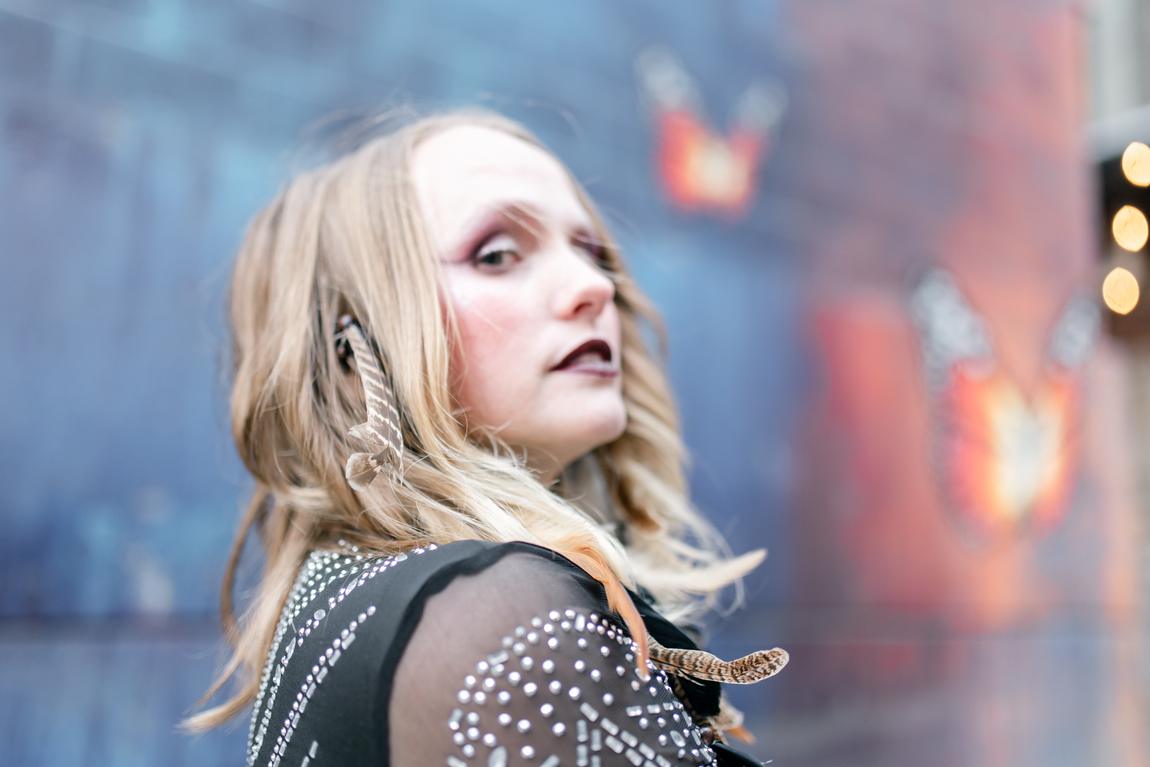 Ariel Jade looking over her shoulder in front of a mural