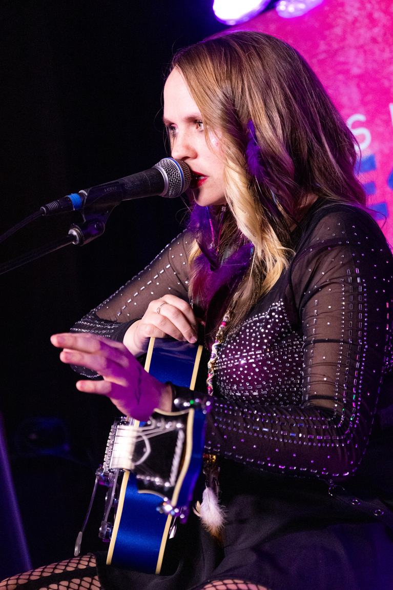 Ariel Jade singing with a blue electric guitar